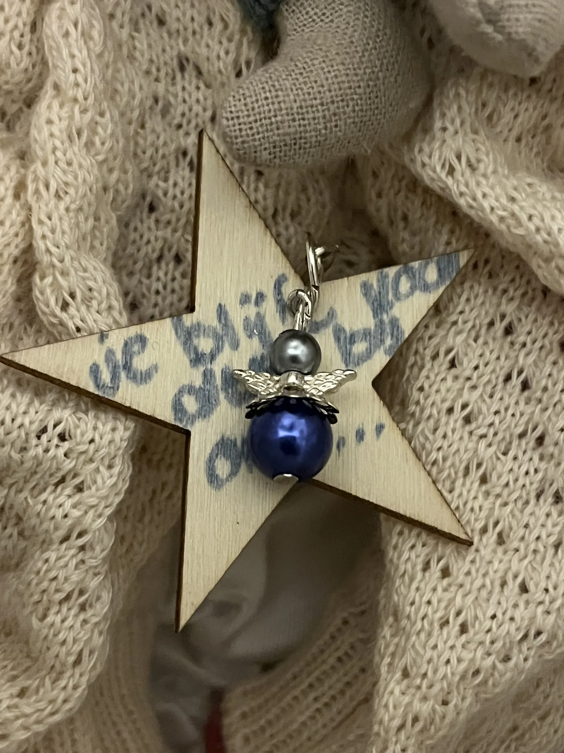Holzstern mit einem kleinen Engel als Erinnerungsstück für ein Sternenkind